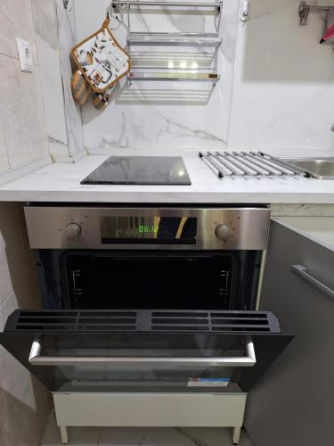 uma cozinha com uma placa de fogão e um forno sentado sob um balcão em Comfortable near metro by hospitality gr em Atenas