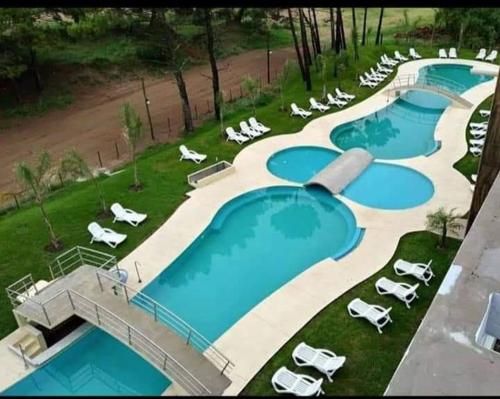 an overhead view of two swimming pools with lawn chairs at depto pinamar in Pinamar