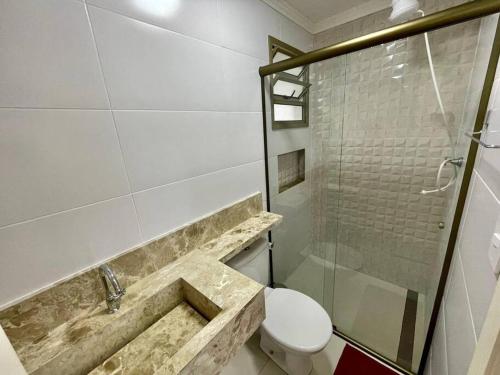 a bathroom with a sink and a toilet and a shower at Apartamento no Canto do Forte - Praia Grande in Praia Grande
