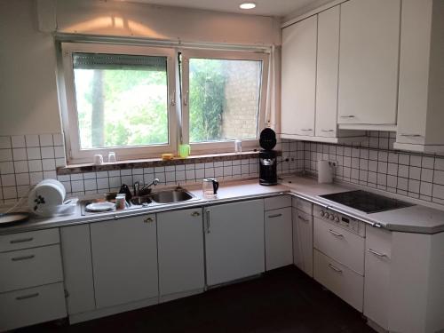 una cucina con armadi bianchi, lavandino e finestra di AH G3 EG a Schwalmtal