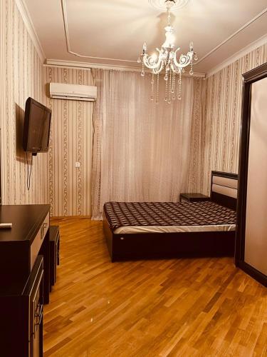 een slaapkamer met een bed, een televisie en een kroonluchter bij F1 Track View Balcony ZARIFA ALIEVA Street in Baku