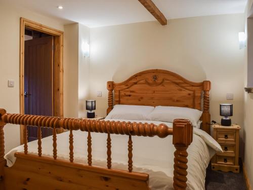 a bedroom with a wooden bed and a wooden staircase at Little Jacks Cottage in Todmorden