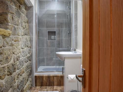 a bathroom with a shower with a sink and a sink at Little Jacks Cottage in Todmorden