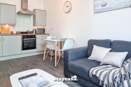 uma sala de estar com um sofá azul e uma cozinha em Spacious Central Apartment With Great Transports em Stockport