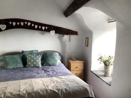 a bedroom with a bed with blue sheets and a window at Top Cottage in Barmouth