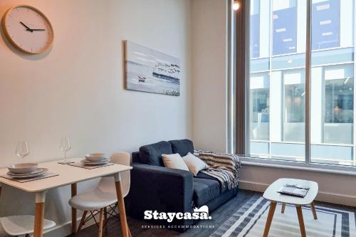 a living room with a couch and a table and a clock at Bright & Central Apt - With Great Transport Links in Stockport
