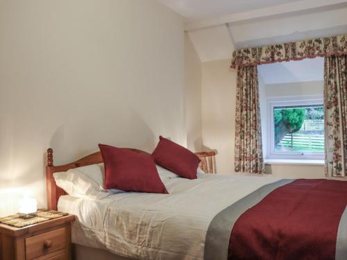a bedroom with a bed with red pillows and a window at Plas Madog in Llanuwchllyn