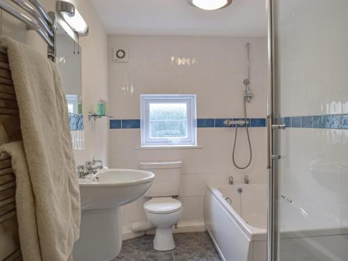 een badkamer met een wastafel, een toilet en een douche bij Cowslip Cottage in Roch