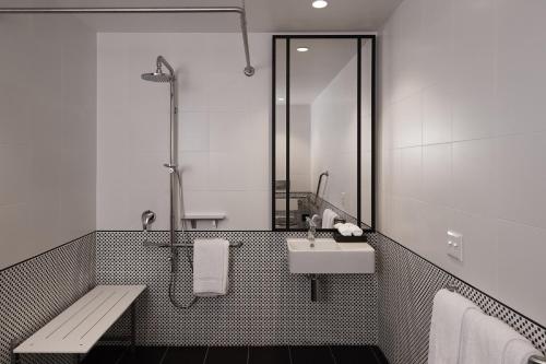 a bathroom with a sink and a shower and a bench at Hotel X Brisbane Fortitude Vly, Vignette Collection by IHG in Brisbane