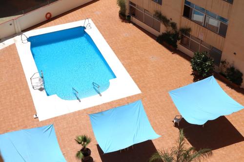 una vista sul tetto di una piscina con ombrelloni blu di Nature Apartment a Torremolinos