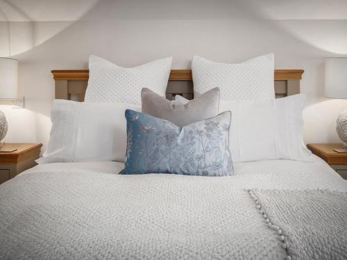 a white bed with white pillows on it at Cranford Cottage in Saint Brides