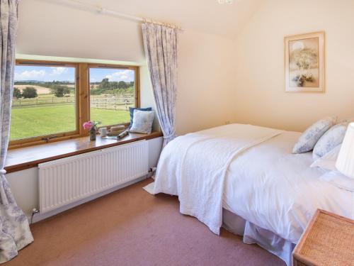 1 dormitorio con cama y ventana en Little Swinton - Garden Cottage, en Swinton