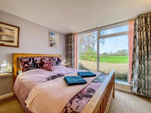 a bedroom with a bed and a large window at Fieldview Snug in Penselwood