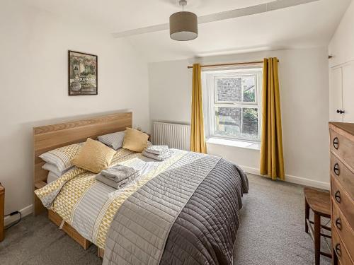 a bedroom with a bed with yellow curtains and a window at Holme Cottage in Embsay