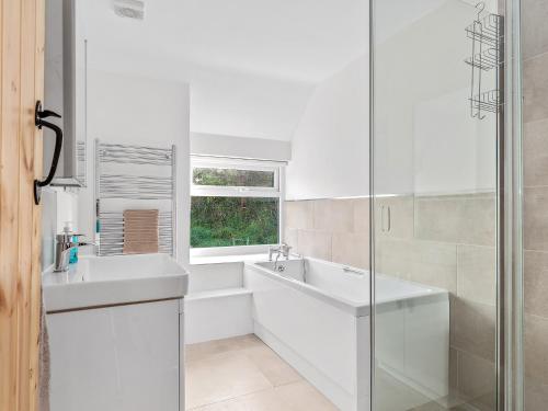 a white bathroom with two sinks and a glass shower at Morfa Ganol in Llangranog