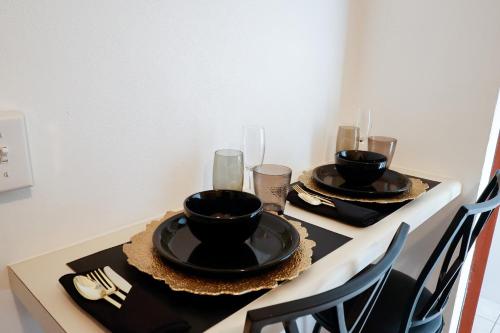 un tavolo con due piatti neri e bicchieri sopra di C&D Residential Penthouse a The Valley
