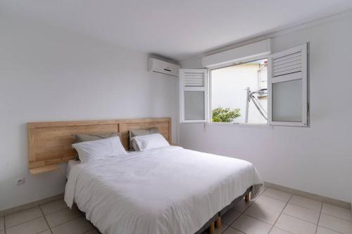a bedroom with a large white bed with a window at Kaz Mitan in Les Trois-Îlets