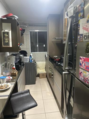 uma pequena cozinha com um balcão e um frigorífico em Lindo apartamento de 2 quartos com suite e sacada com churrasqueira em Pinhais