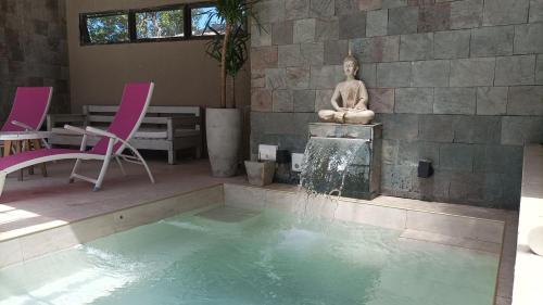 Ein Pool mit einer Statue einer Frau, die auf einem Brunnen sitzt. in der Unterkunft La Morada Apart Boutique & Spa in Villa Gesell