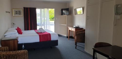 a hotel room with a bed and a window at Commodore Motor Lodge in Ashburton
