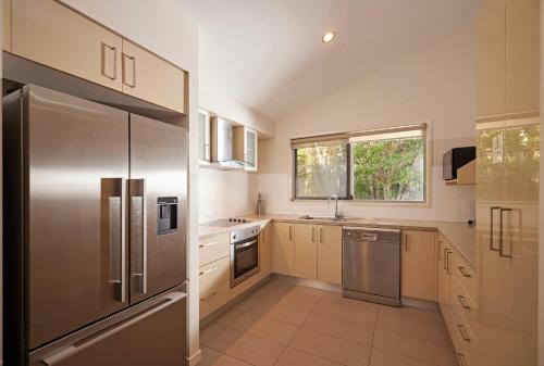 a kitchen with a stainless steel refrigerator and a window at Brisbane Holiday Village in Brisbane