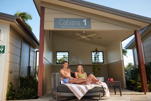 a man and a woman sitting on a bed on a porch at Brisbane Holiday Village in Brisbane