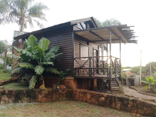 a small house with a porch on a stone wall at Cabañas Misioneras in San Ignacio