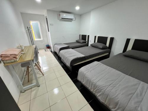 a room with three beds and a desk in it at K SUITES HOTEL in Chabang Tiga