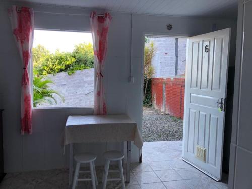 eine Küche mit einem Tisch und zwei Hockern neben einem Fenster in der Unterkunft Hospedaria Mirante da maré ap6 in Imbituba