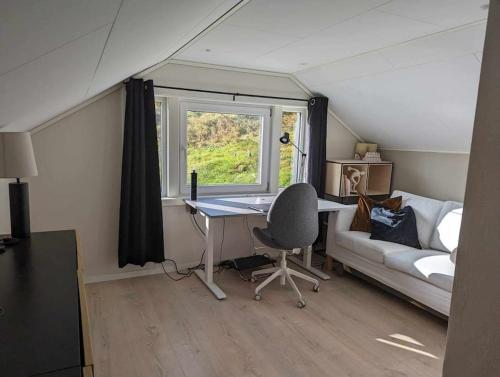 um quarto com uma secretária, um sofá e uma janela em Nyoppusset hus med utsikt. em Steinkjer