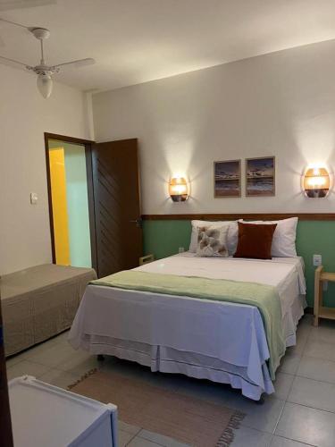 een slaapkamer met een bed en twee lampen aan de muur bij Villa Aconchego Guarajuba in Camaçari
