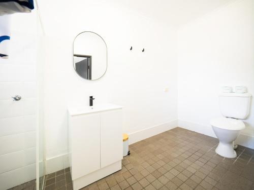a white bathroom with a toilet and a mirror at YHA Cape Byron, Byron Bay in Byron Bay