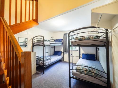 a bunk bed room with two bunk beds and a staircase at YHA Cape Byron, Byron Bay in Byron Bay