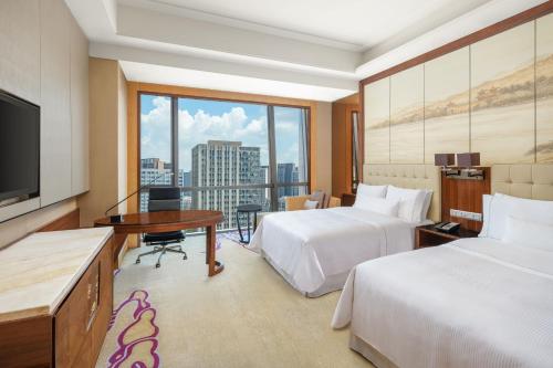 um quarto de hotel com duas camas e uma televisão de ecrã plano em The Westin Wuhan Wuchang em Wuhan