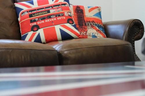 a brown leather couch with a red and blue pillow at Private Bright Modern Studio! Queen bed ! in Victoria