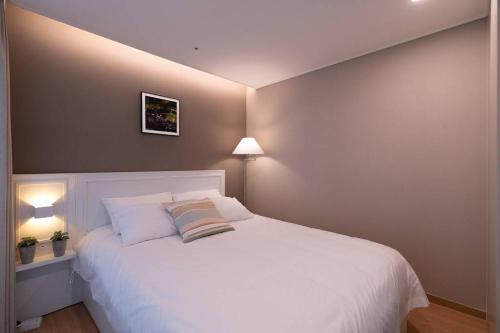 a bedroom with a large white bed with two pillows at Haeundae Ocean Family in Busan
