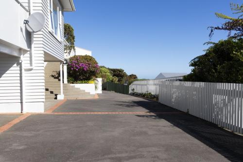 an empty street next to a white fence at Khandallah Harbour View BnB in Wellington