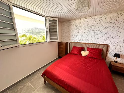 Schlafzimmer mit einem roten Bett und einem großen Fenster in der Unterkunft Havre de paix, en atlantique ! in Sainte-Marie