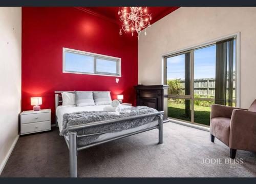- une chambre dotée d'un mur rouge avec un lit et une chaise dans l'établissement Freestanding house with ocean view, à Port Campbell