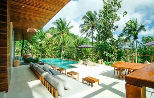an outdoor patio with a pool and tables and chairs at EMHILL Estate Lombok in Selong Belanak