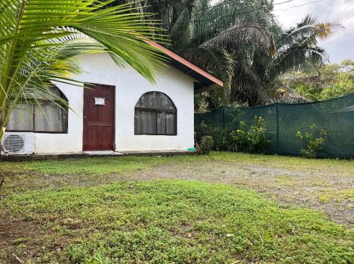 una pequeña casa con una puerta roja y una valla en Casa Coco en Puerto Jiménez