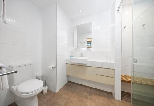 a white bathroom with a toilet and a sink at Brisbane Holiday Village in Brisbane