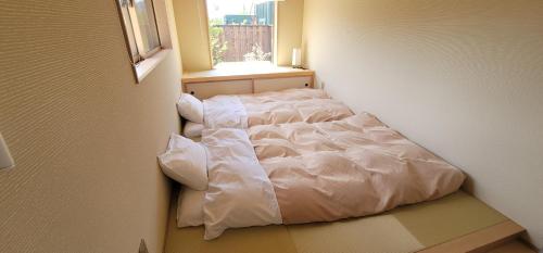 uma cama branca num quarto com uma janela em 河口湖ベースキャンプ登り坂 em Azagawa