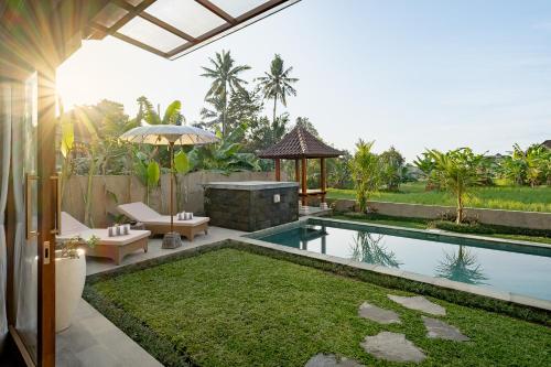 a villa with a swimming pool and an umbrella at Suarga Loka Ubud Villa in Ubud