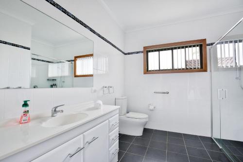 a white bathroom with a sink and a toilet at Tangerine - Pet Friendly - 3 Mins Walk to Beach in Sanctuary Point