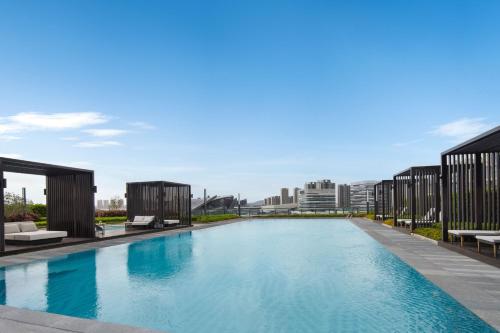 a large swimming pool with chairs and buildings in the background at Zhuhai Marriott Hotel Jinwan in Zhuhai