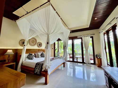 a bedroom with a canopy bed with white curtains at The Papas Villas in Tegalalang