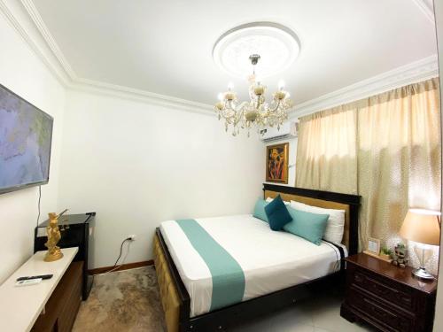 1 dormitorio con cama y lámpara de araña en Habitación a cinco minutos del aeropuerto y terminal terrestre, en Guayaquil