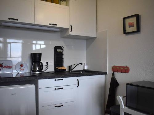 a kitchen with white cabinets and a black counter top at Studio Font-Romeu-Odeillo-Via, 1 pièce, 2 personnes - FR-1-580-102 in Font-Romeu-Odeillo-Via