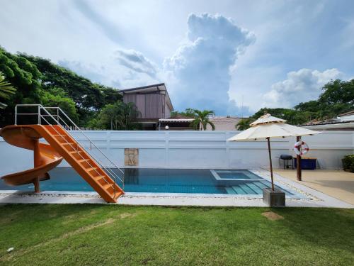 a swimming pool with a staircase and an umbrella at ทิวาพูลวิลล่า หัวหิน Thiva Pool Villa Hua Hin in Hua Hin